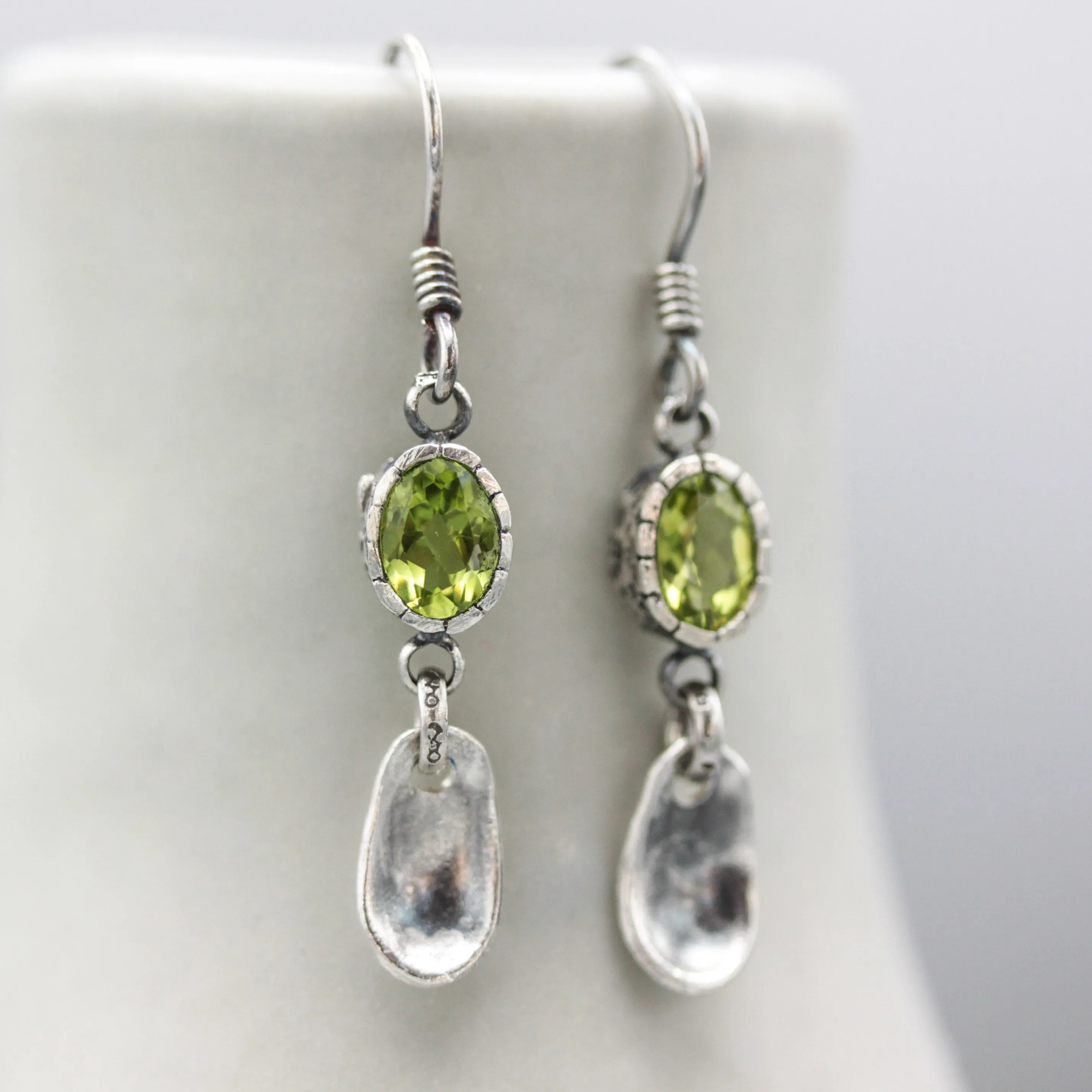 Oval Peridot earrings in silver bezel setting with silver leaf on sterling silver hooks style
